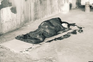 Homeless man sleeping in sleeping bag on cardboard